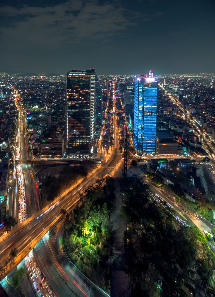 A stunning aerial cityscape of Mexico City at night, showcasing illuminated skyscrapers and bustling traffic.
